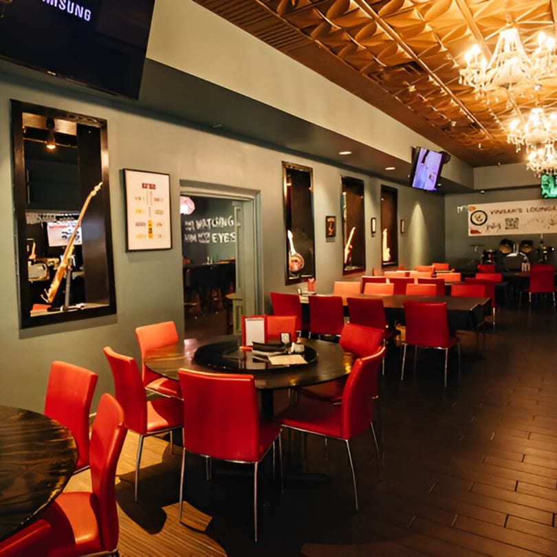 Vinsar's Lounge dining area with red chairs, dark tables, and a decorative ceiling with chandeliers.