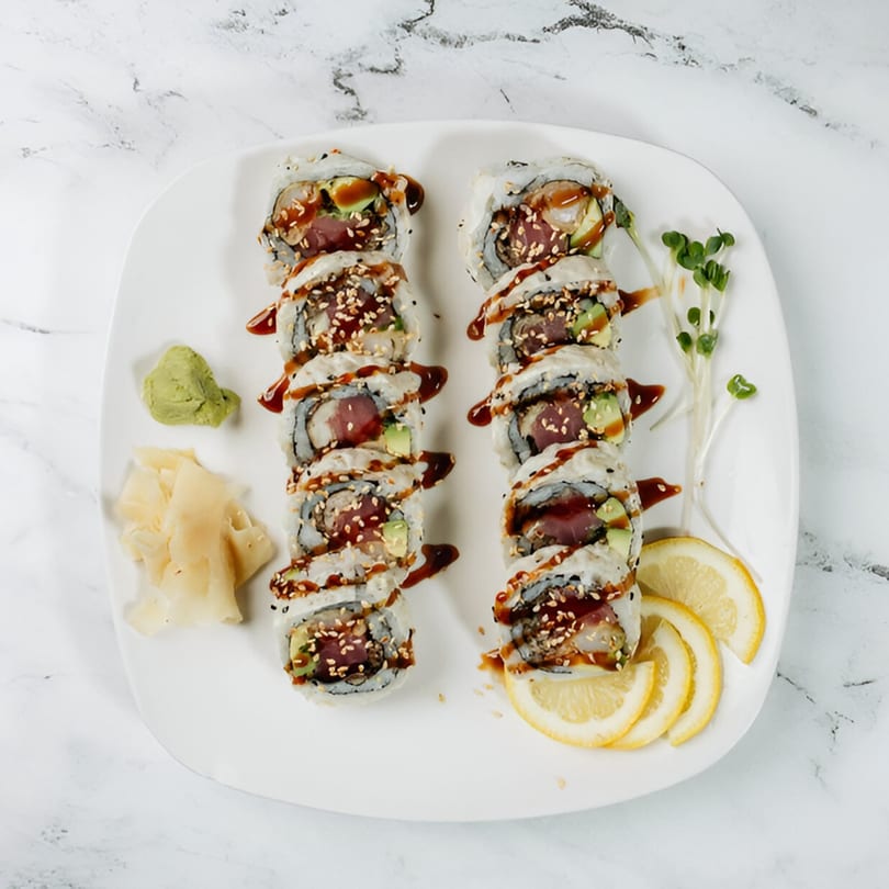 Two rows of Vinsar's Lounge Asian-fusion sushi rolls with tuna, avocado, sauce, sesame seeds, and lemon.